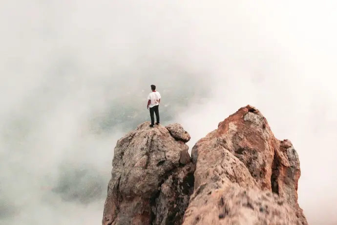 Personne debout sur un sommet rocheux, illustrant la capacité de la vidéo à capturer instantanément l'attention dans un monde numérique saturé.